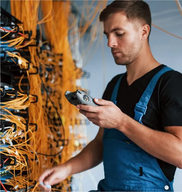 WallaceWilliam low voltage technician testing fiber terminations inside a New York City network closet